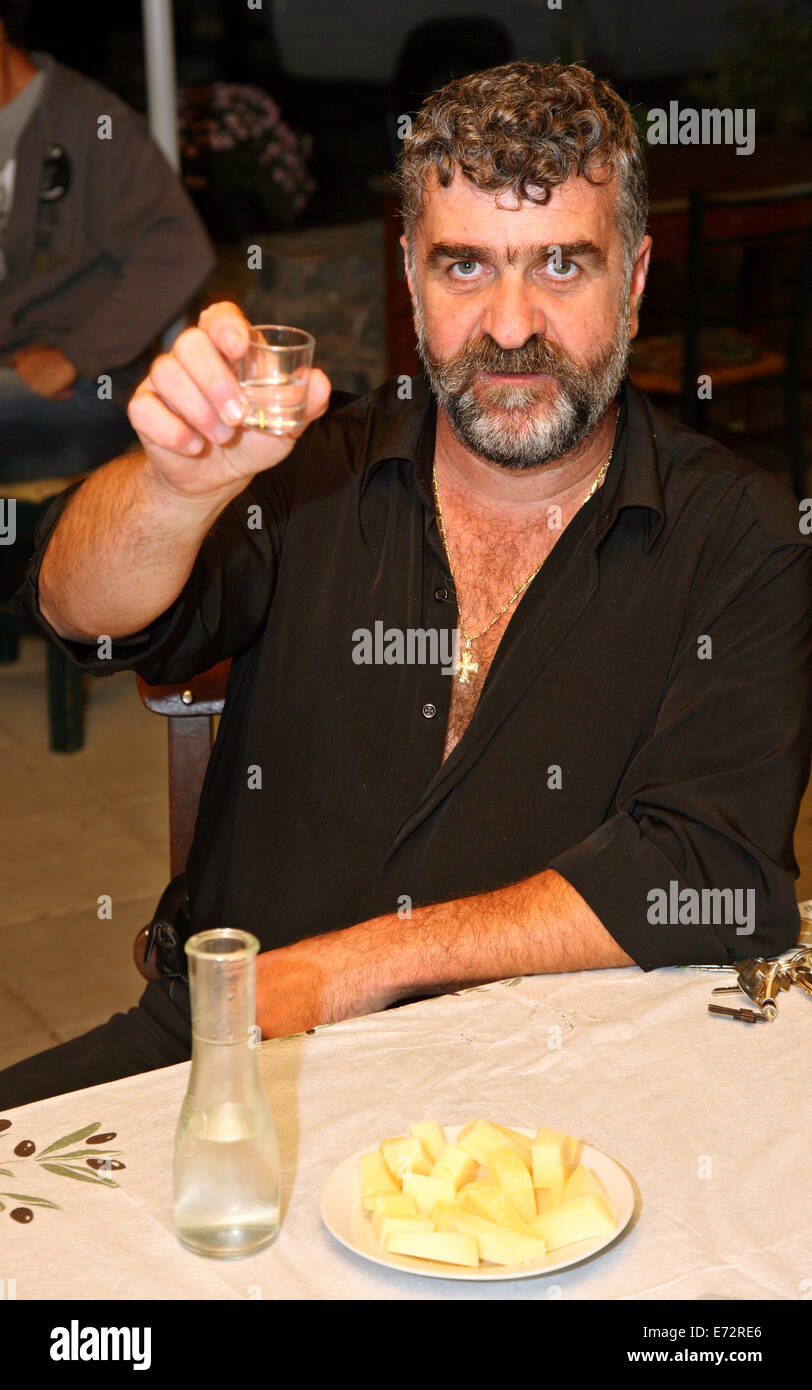 "Cheers" von einem kretischen Mann mit Raki (oder "Tsikoudia"), das traditionelle Getränk Kretas. Im Karidi Village, Lassithi, Griechenland. Stockfoto