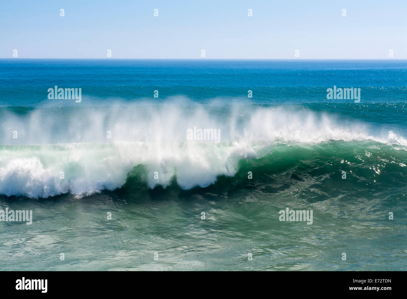 Eine schöne und leistungsstarke türkise Welle bei starkem Wind locken beim weißen Spray Nebel Formen und auf seine Kuppe in Huntington Beach. Stockfoto