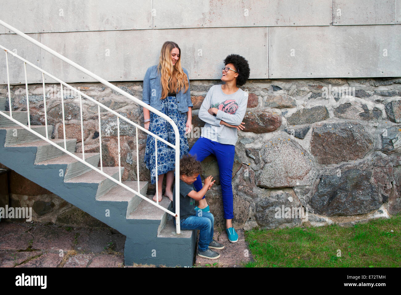 Anzeigen von Mädchen im Teenageralter mit jungen (2-3) auf Treppen (13-15, 16-17) Stockfoto