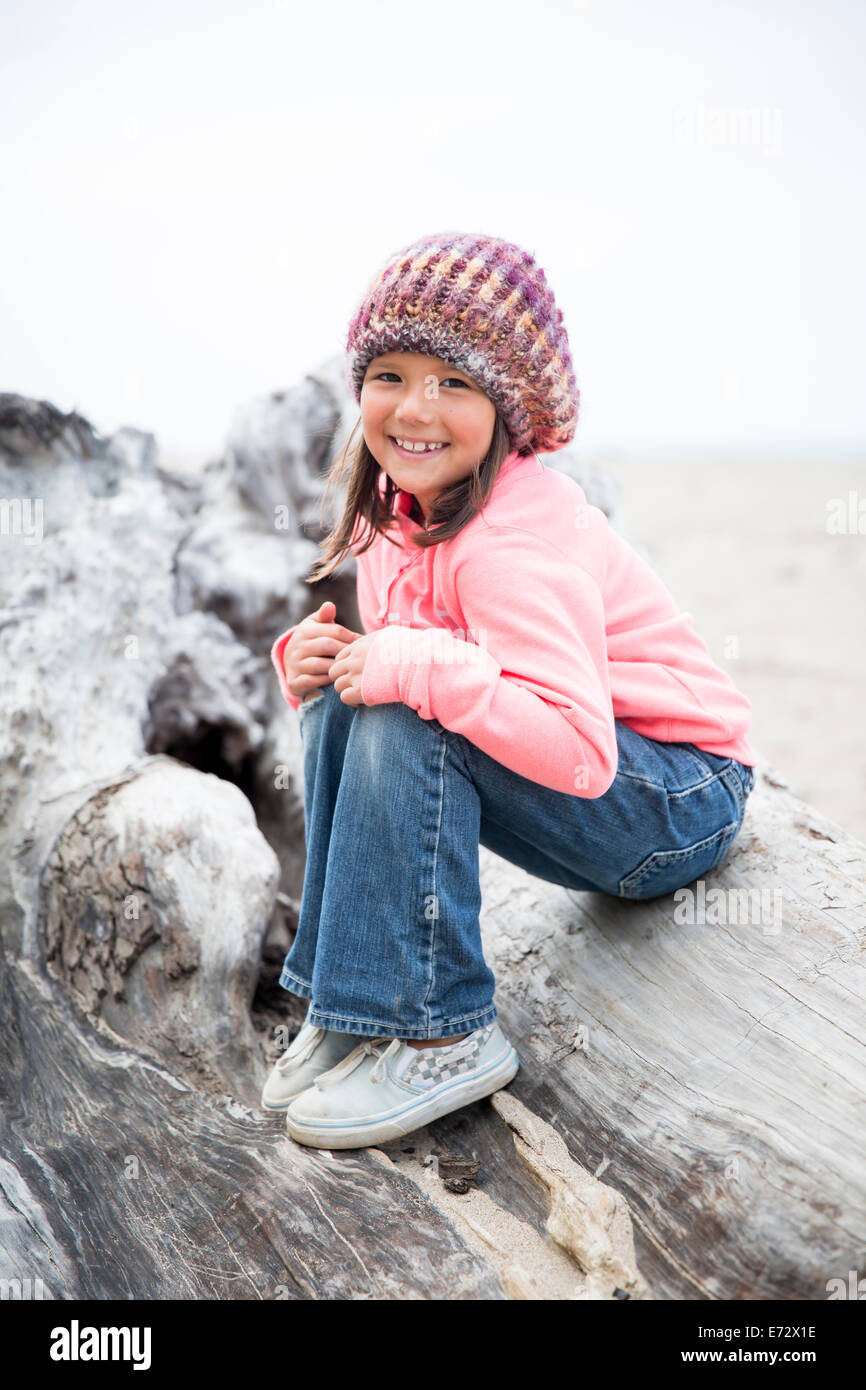 Glückliches Mädchen (6-7) auf Fels sitzend Stockfoto