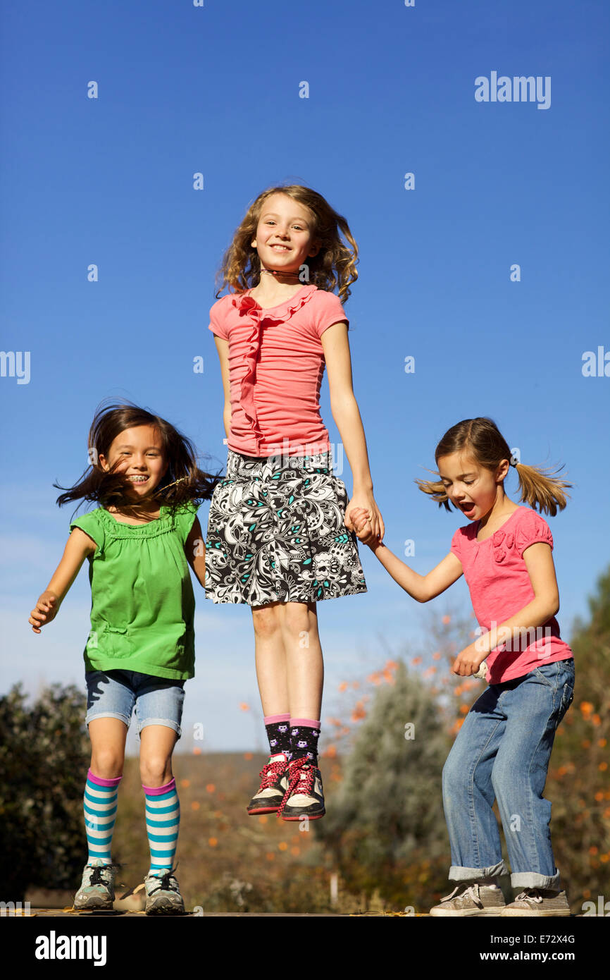 Mädchen (8-9, 10-12) Hand in Hand und springen Stockfoto