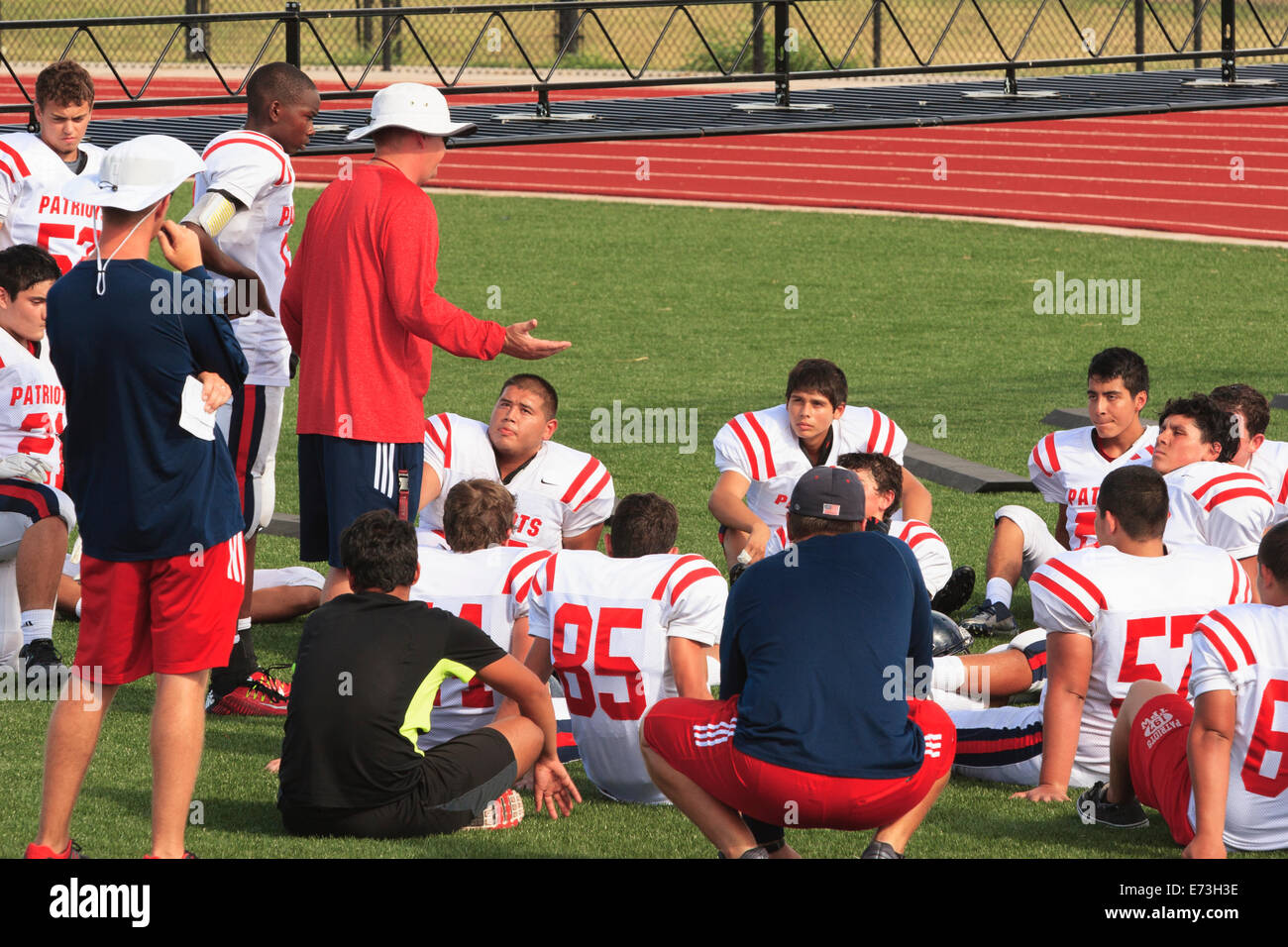 Amerikanische High School Fußball-Trainer im Gespräch mit Junior Varsity Football Team während des Spiels Halbzeit Stockfoto
