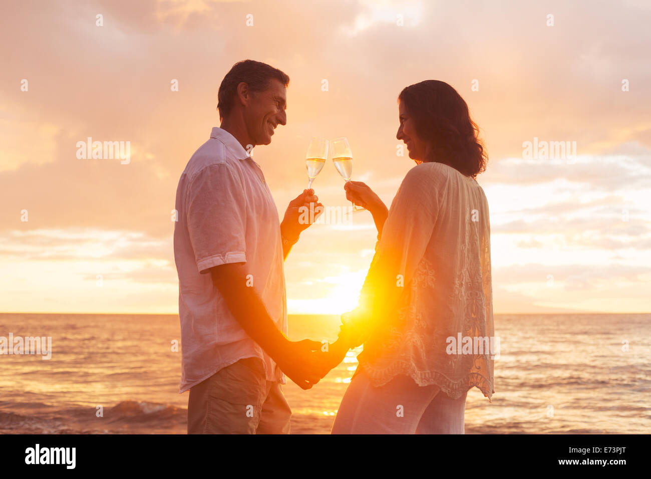 Romantisches Brautpaar Glas Champagner bei Sonnenuntergang am Strand genießen. Urlaub-Reisen-Ruhestand-Jahr-Feier. Stockfoto