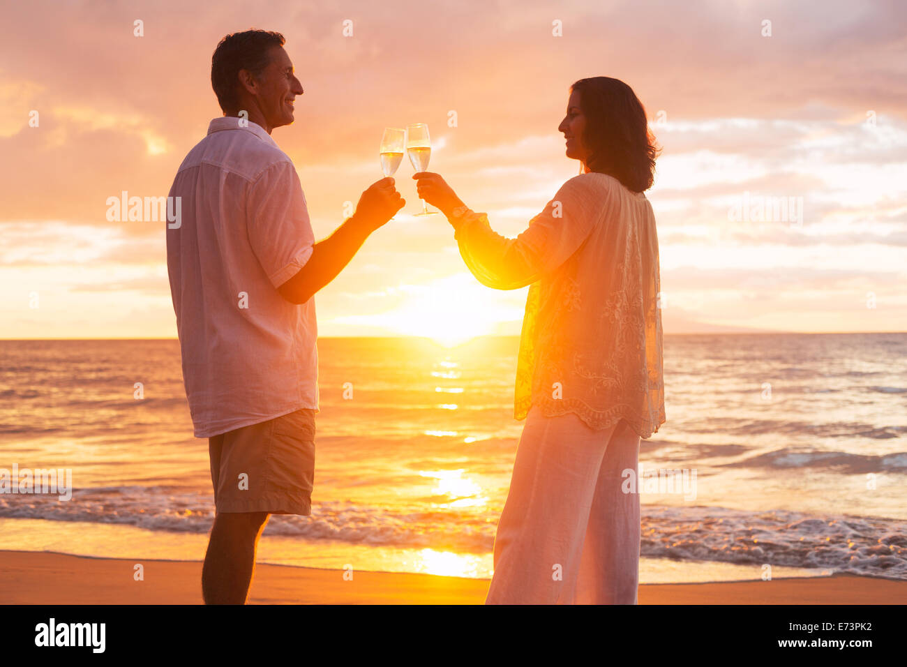 Glücklich romantische älteres Paar Glas Champagner bei Sonnenuntergang am Strand genießen Stockfoto