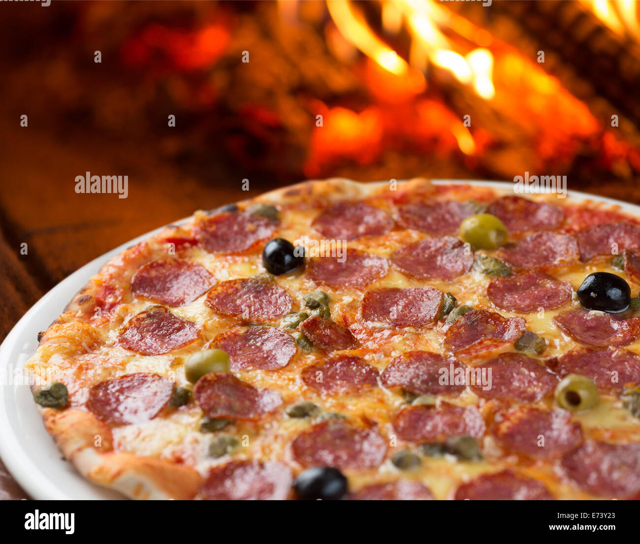 Traditionelle Pizza mit Salami, Kapern und Oliven im Ofen backen Stockfoto