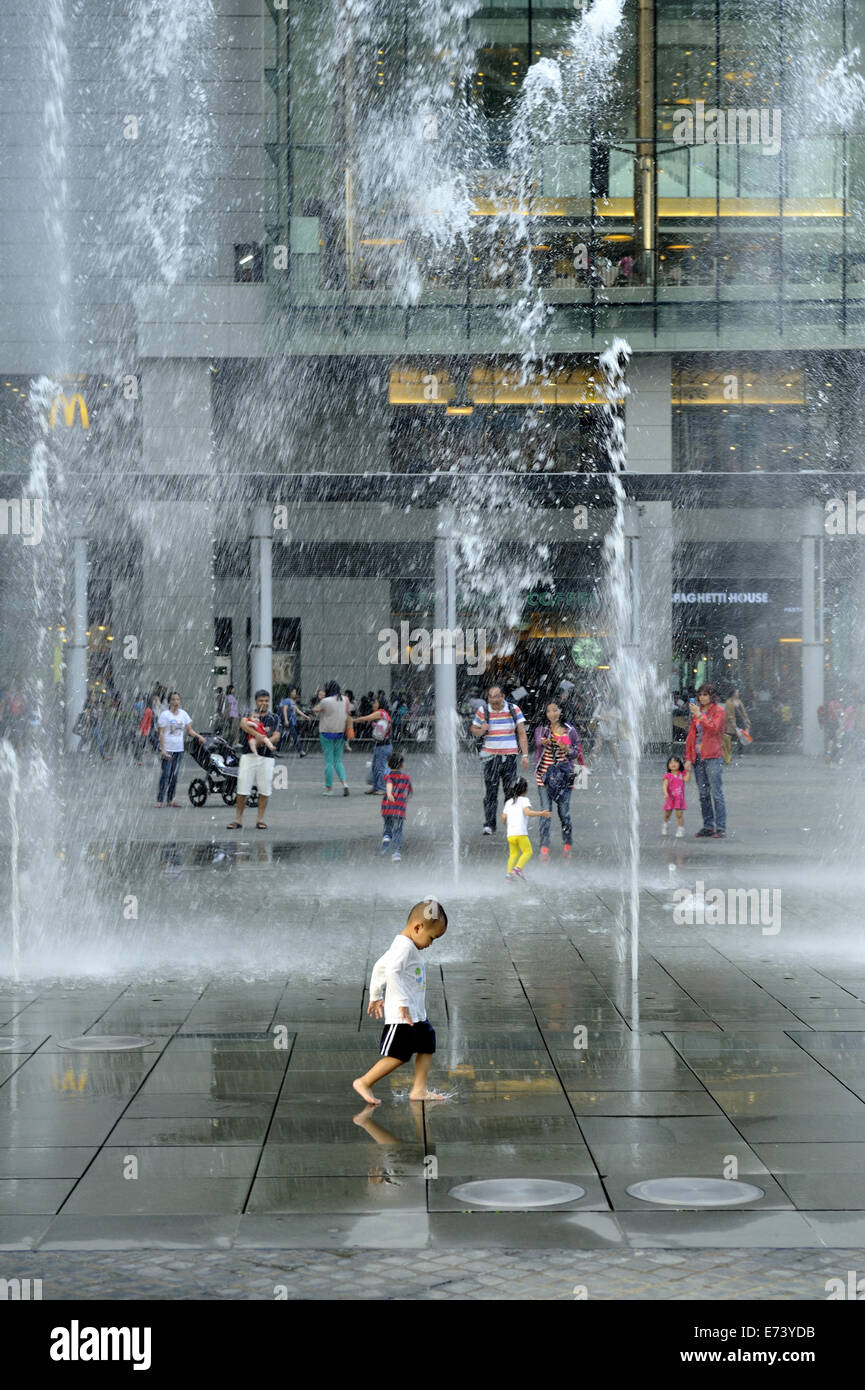 Kind spielt in Wasserfontänen in öffentliche Freifläche in der Nähe der Seilbahnstation, Tung Chung, Lantau Island, Hong Kong, China Stockfoto