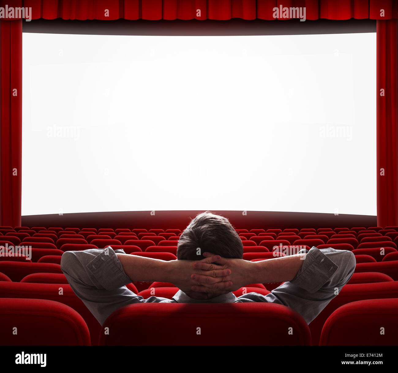 ein entspannter Mann allein mit Komfort wie zu Hause zu sitzen vor großen Leinwand im leeren Kinosaal Stockfoto