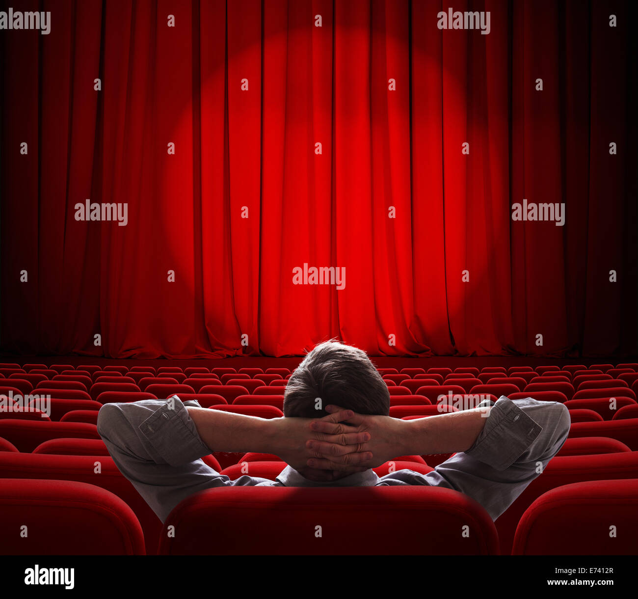 Mann sitzt allein in leeren Theater oder Kino-Saal Stockfoto