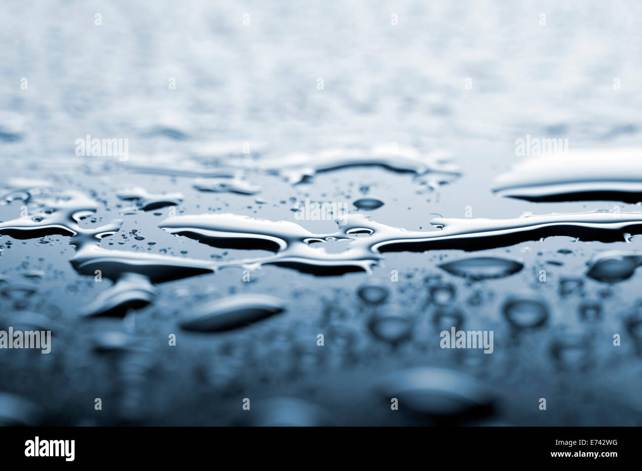 Wassertropfen auf blaue Fläche, Schwerpunkt in der Mitte, geringe Schärfentiefe Stockfoto