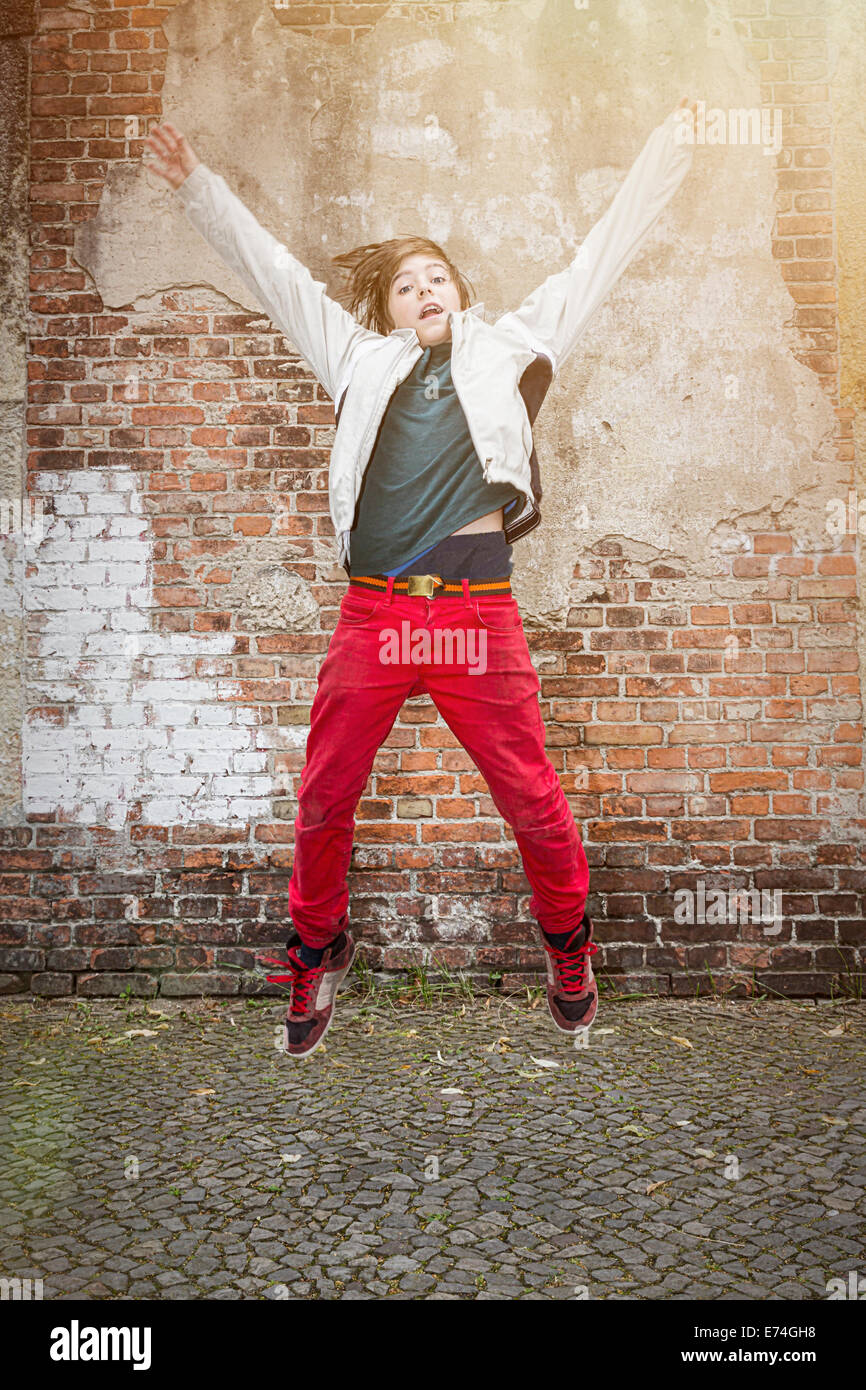 fliegen, springen Teenager Boy vor eine alte Mauer Stockfoto