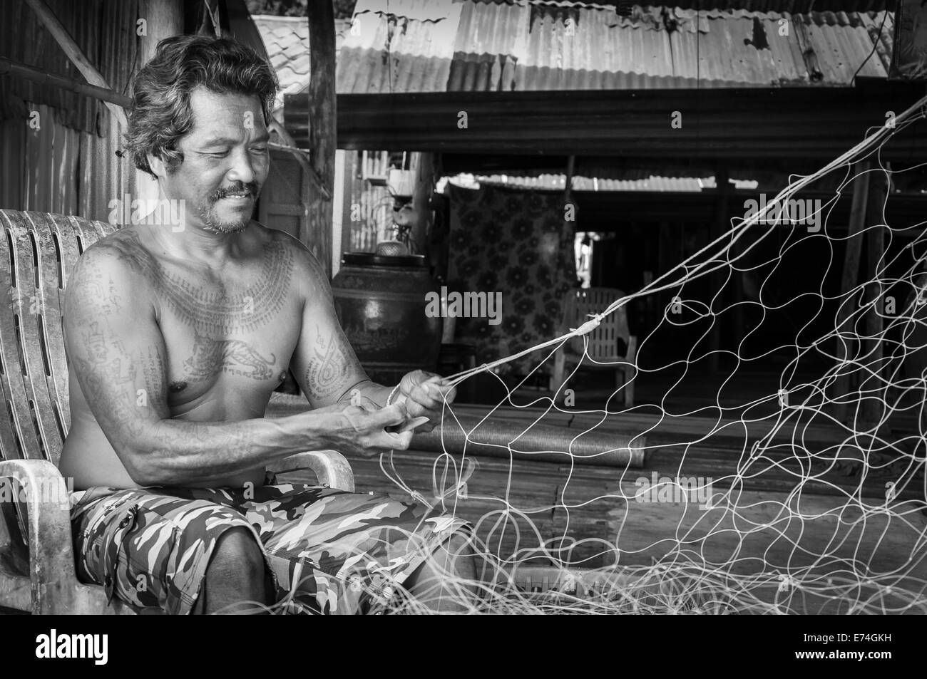 Thai Fischer Flicken sein Fischernetz im Baan AoYai Salat Fischerdorf in Thailand Stockfoto