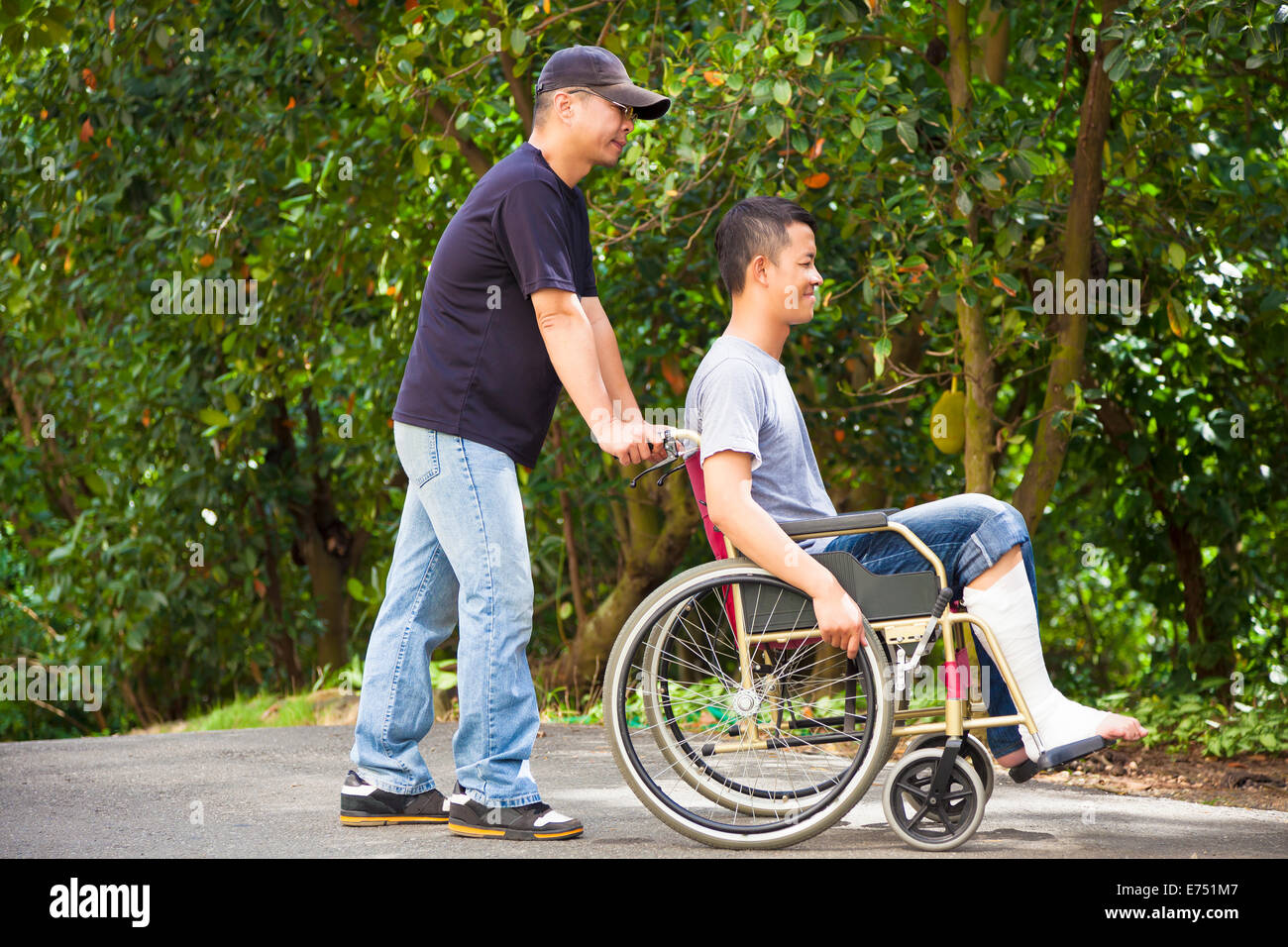 junger Mann sitzt auf einem Rollstuhl mit seinem Bruder Stockfoto