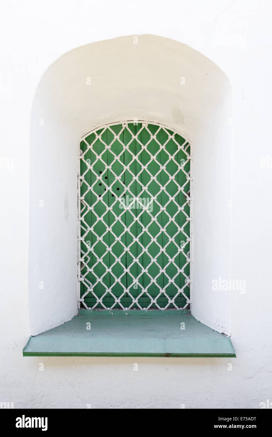 Weiße Wand und grünes Fenster mit Gitter, Hintergrundtextur Stockfoto