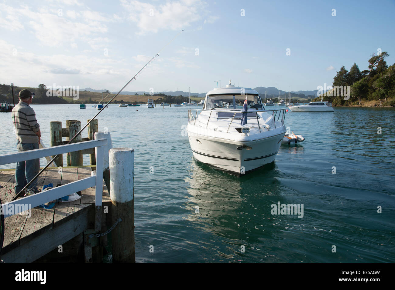 Sandspit New Zealand Tag Kreuzfahrt-Schiff nähert sich der Werft, beobachtet von einem Mann Angeln Stockfoto