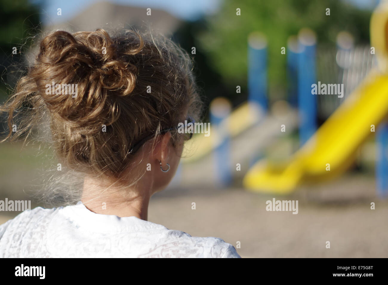 Schulhof-Spielplatz - Profil der Mutter auf dem Spielplatz beobachten Stockfoto