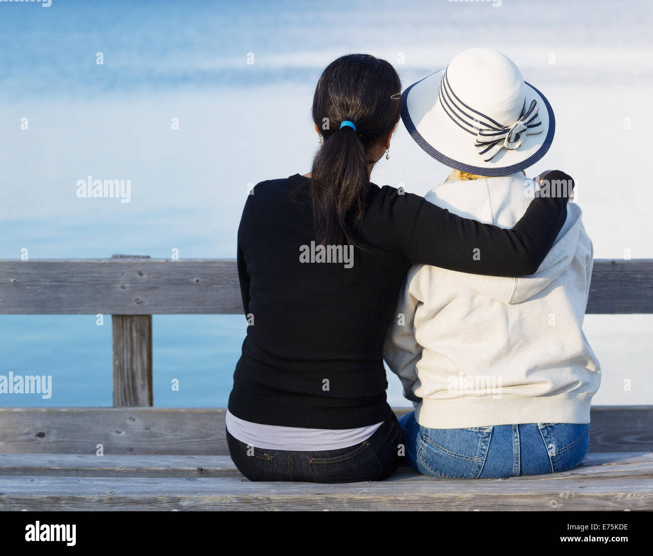 Nahaufnahme von Mutter und ältere Tochter Standortwahl auf Holzbank beim Blick auf den See Stockfoto