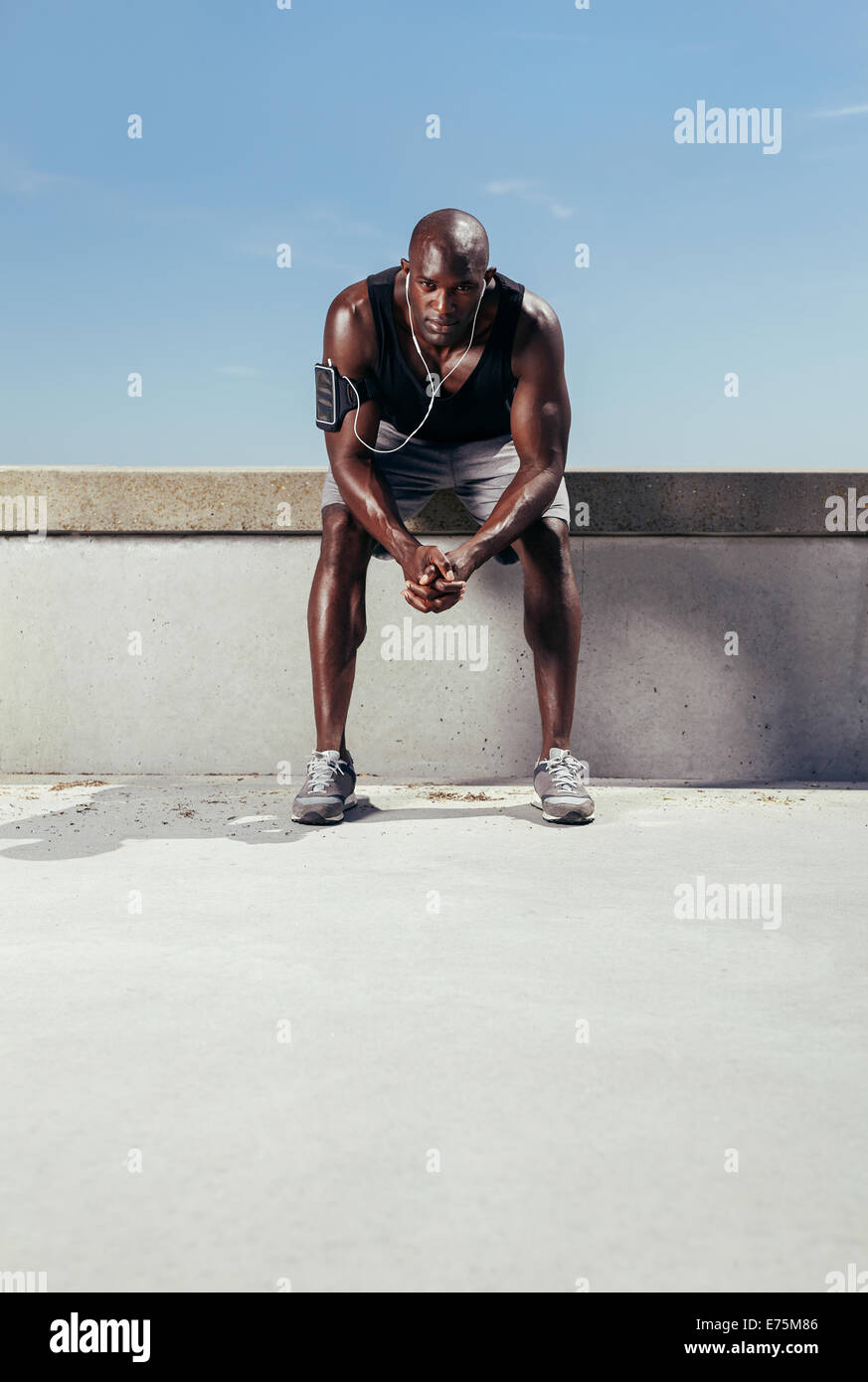 Porträt eines erschöpften Läufers im Freien sitzen. Muskulös und Fit junger Athlet entspannen nach seiner Fitness-Training. Stockfoto