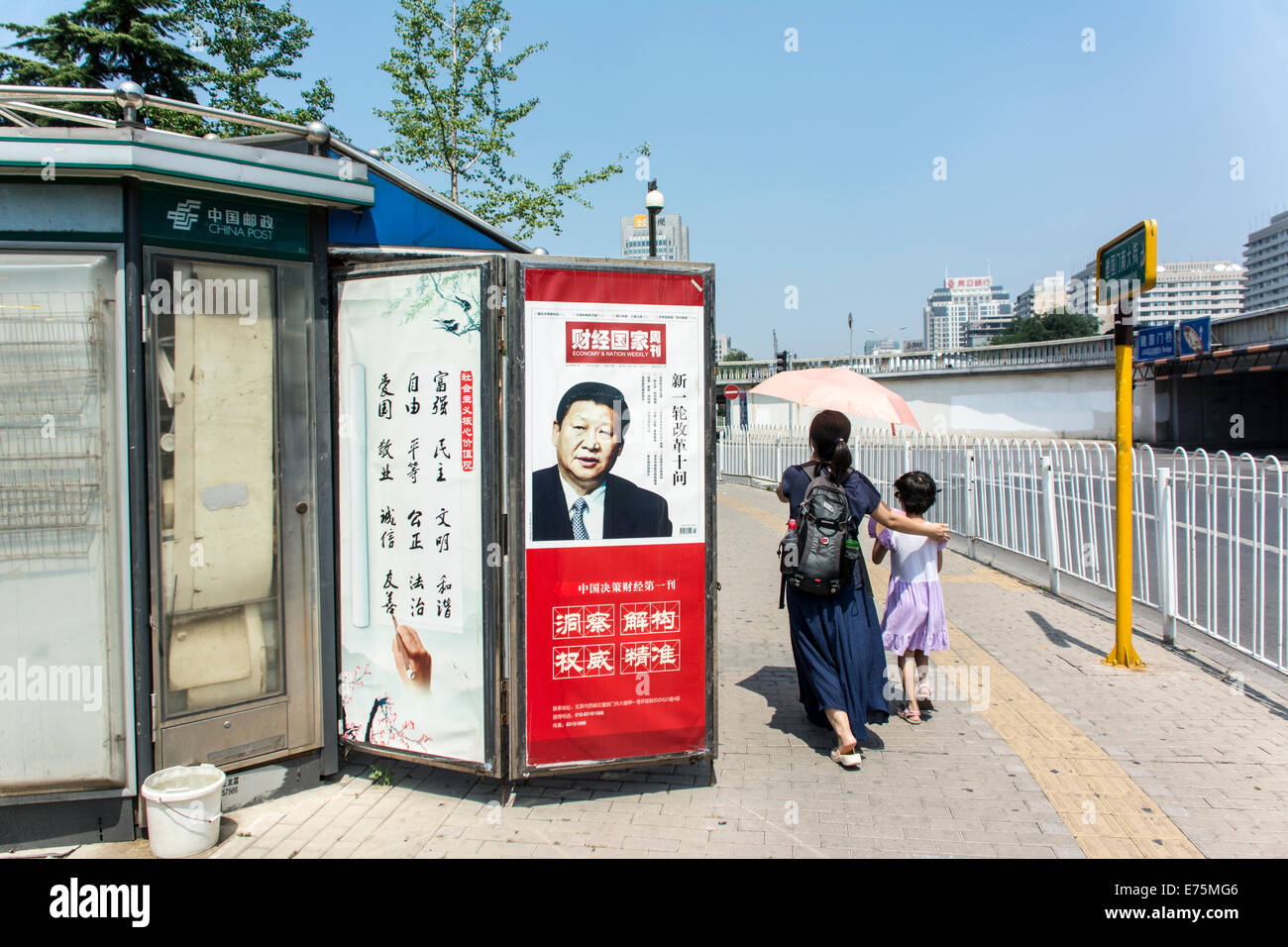 Chinesen, die zu Fuß durch einen Kiosk mit Bild von Präsident Xi Jinping Stockfoto