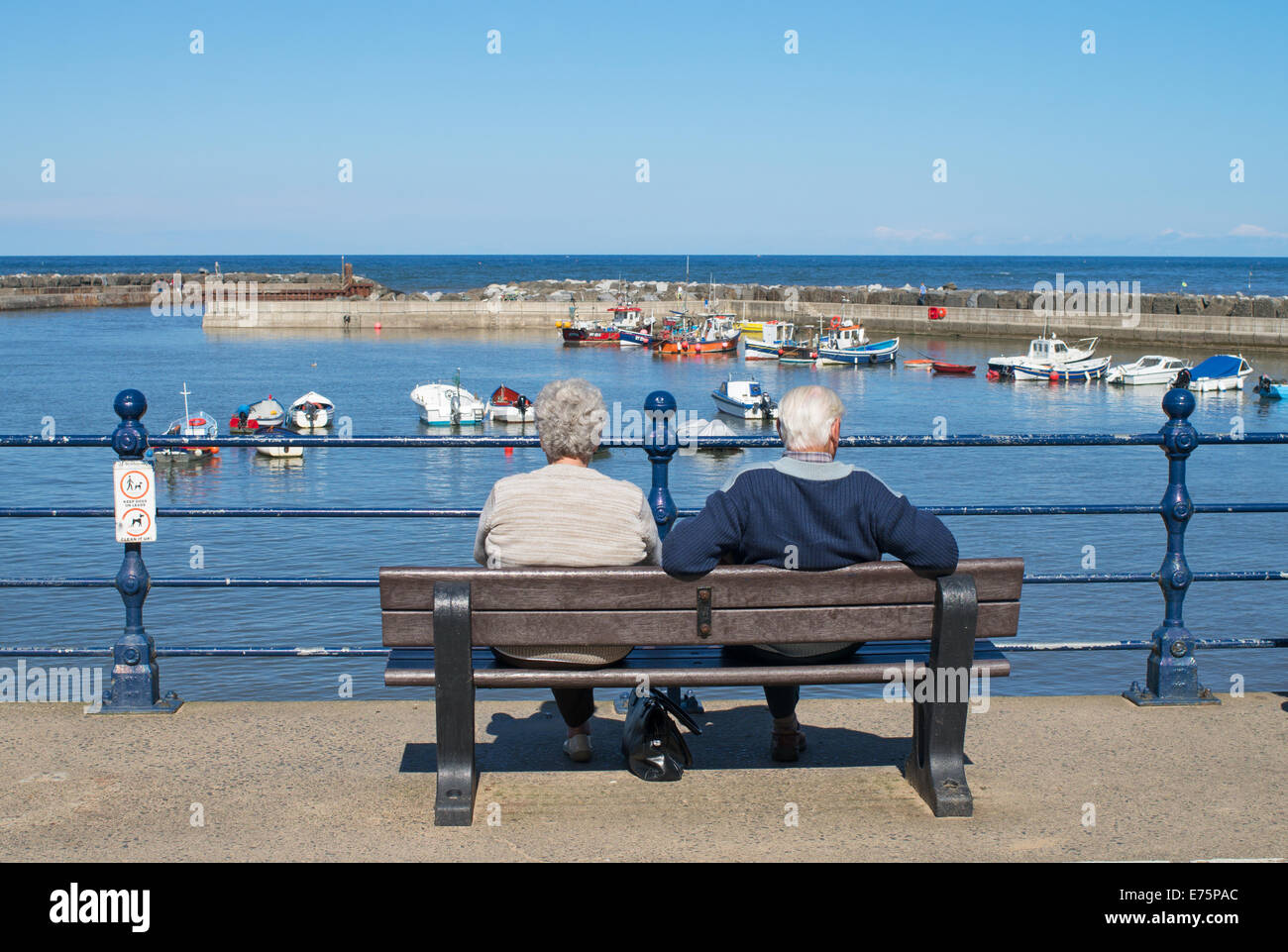 Älteres paar sitzen mit Blick auf die Nordsee Staithes, North Yorkshire, England, UK Stockfoto
