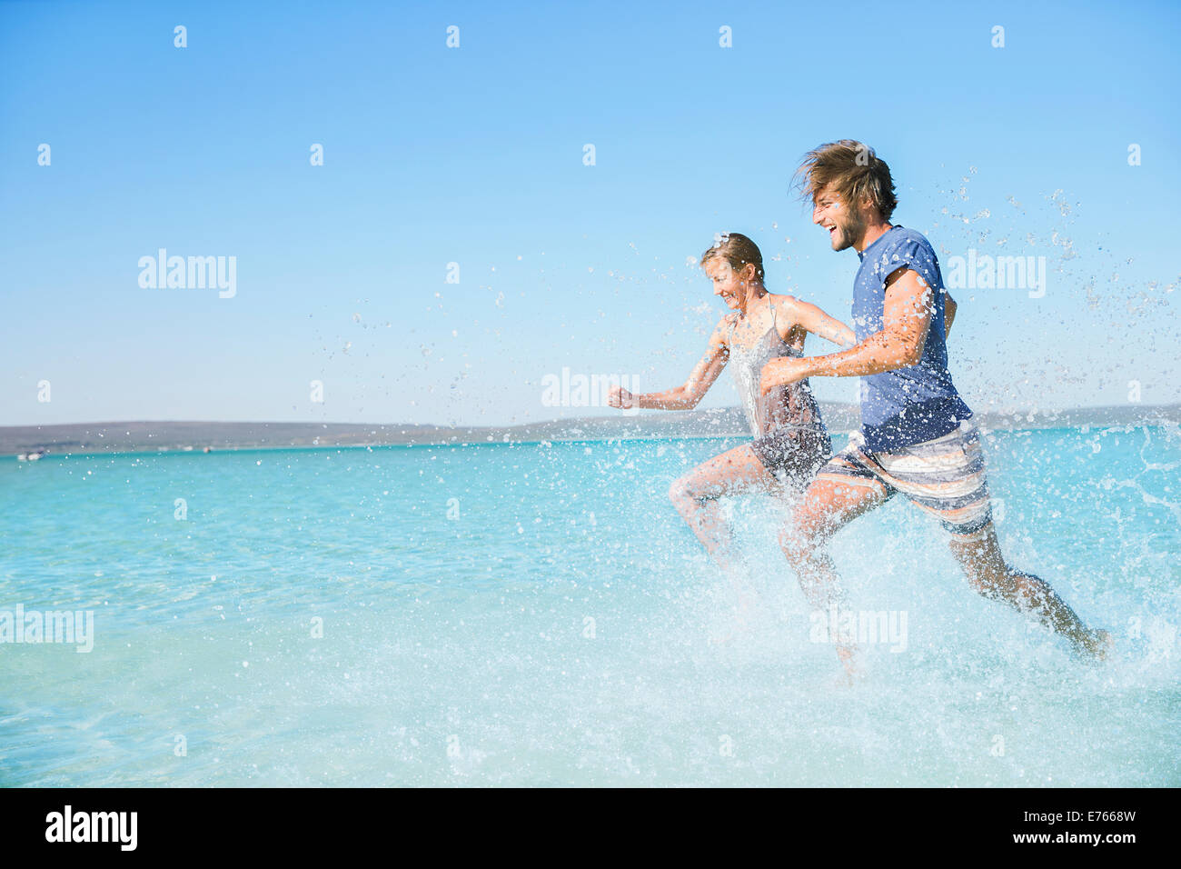 Paar am Strand im Wasser laufen Stockfoto
