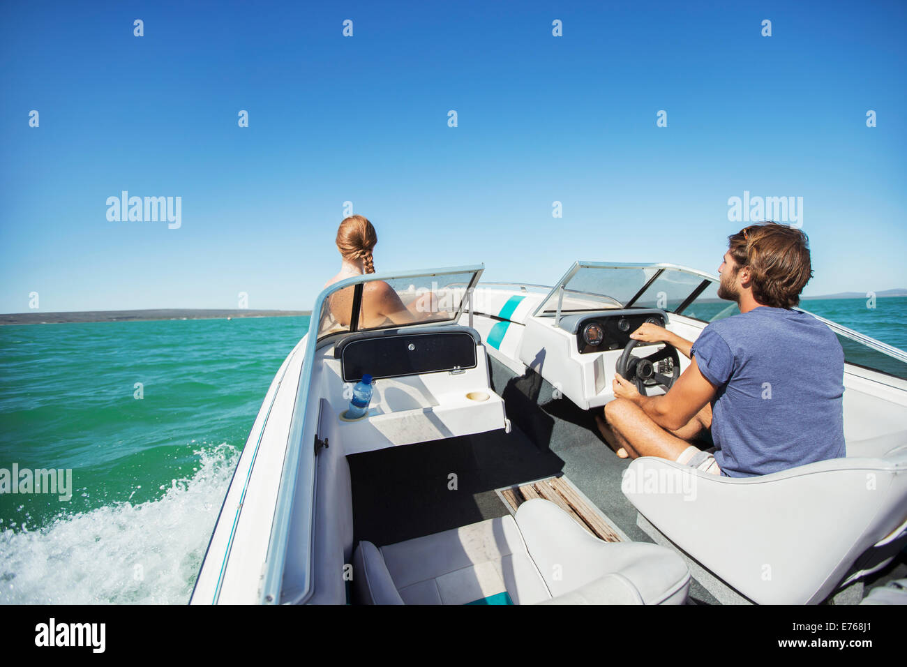 Mann, die Lenkung Boot auf dem Wasser mit Freundin Stockfoto