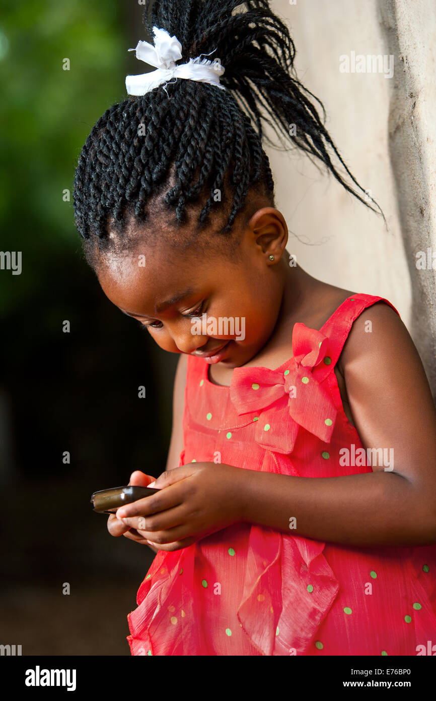 Porträt von netten afrikanischen Mädchen mit geflochtenen Haaren auf smart Phone spielen hautnah. Stockfoto