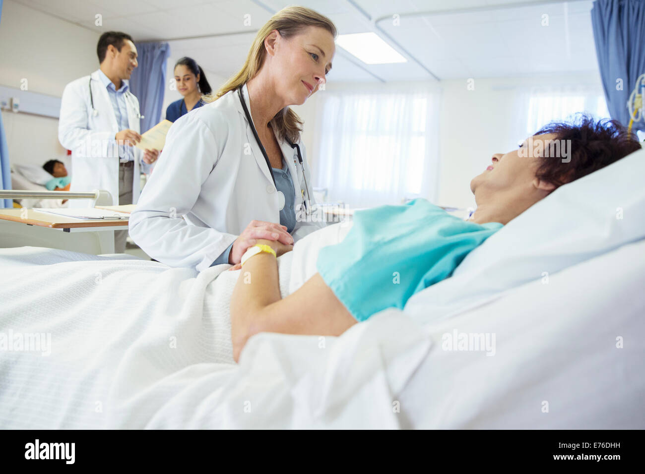 Arzt im Gespräch mit Patienten im Krankenhausbett Stockfoto