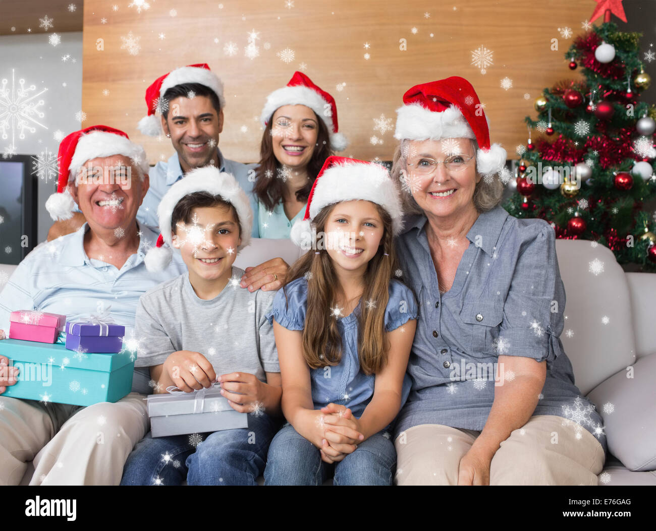 Zusammengesetztes Bild der Großfamilie im Weihnachtsmützen mit Geschenk-Boxen im Wohnzimmer Stockfoto
