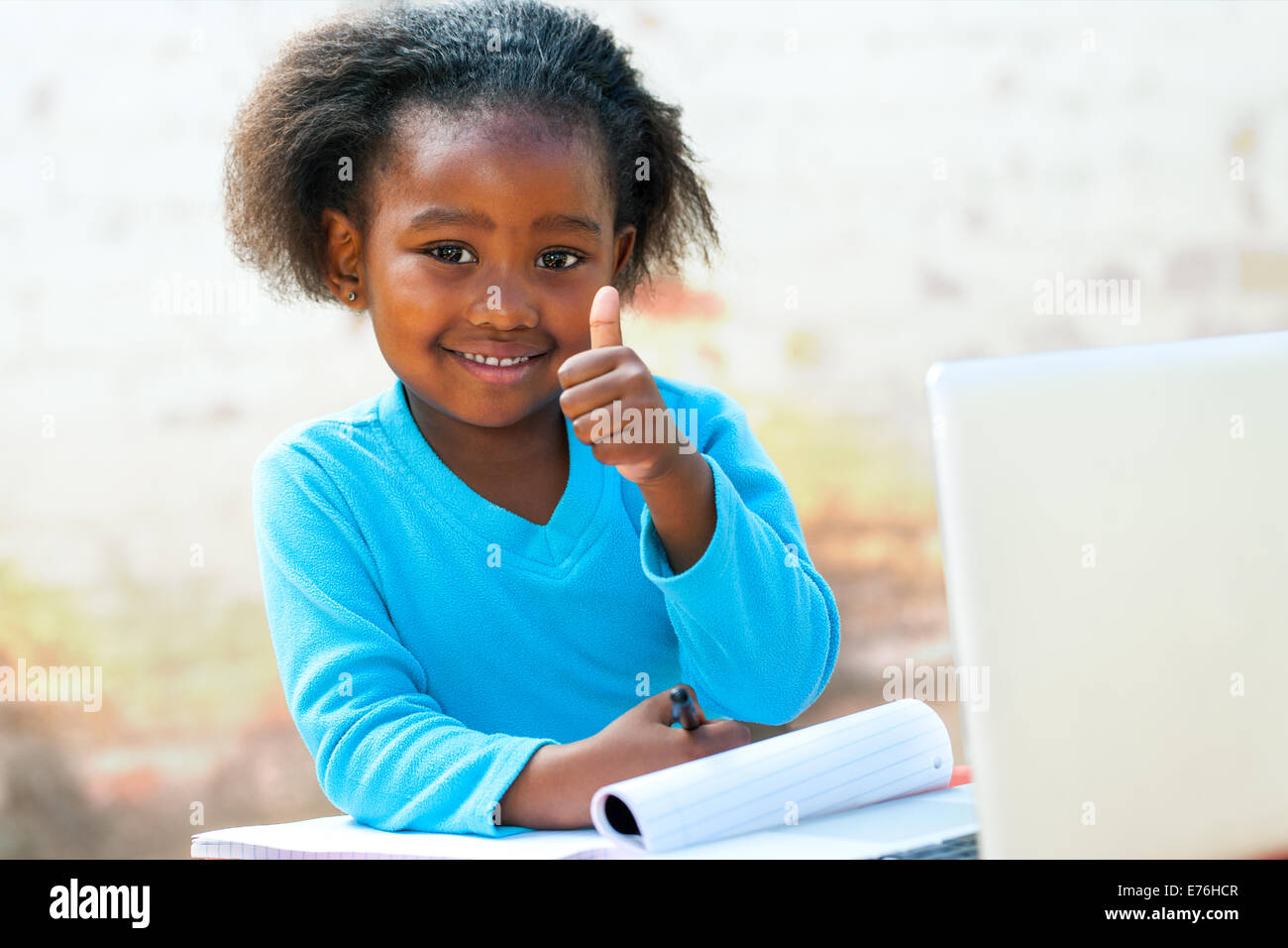 Lächelnd wenig afrikanische Student tun Daumen hoch Seufzer am Schreibtisch. Stockfoto