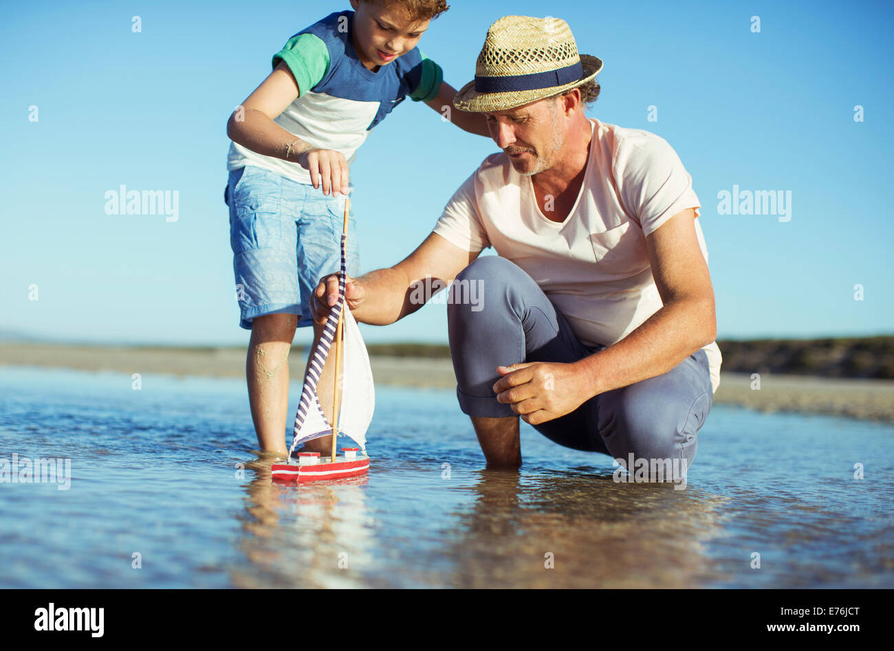 Großvater und Enkel spielen mit Spielzeugboot im Wasser Stockfoto