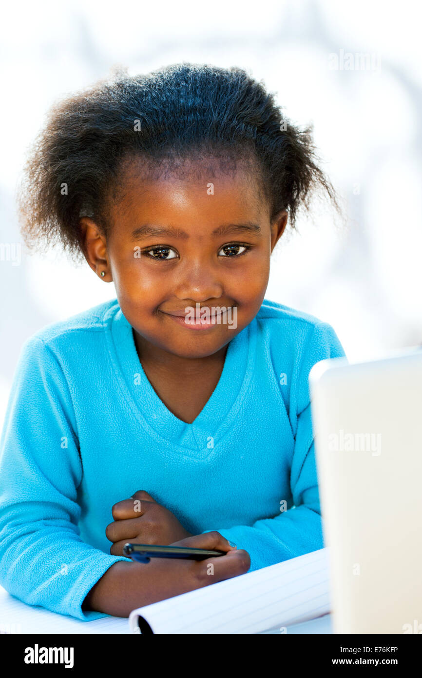 Porträt von einheimischen afrikanischen Kind am Schreibtisch mit Laptop und Notebook. Stockfoto