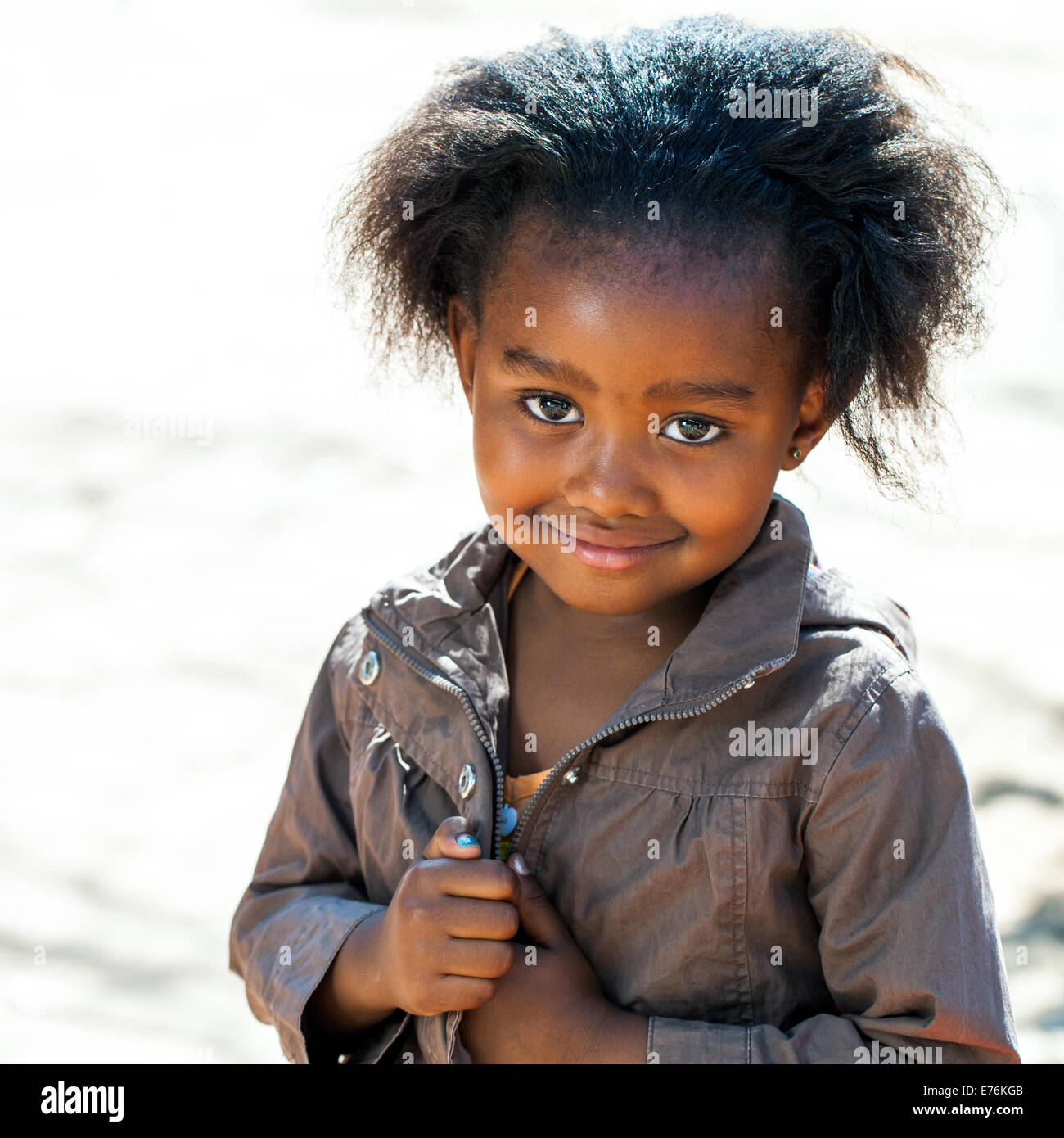 Porträt von kleinen afrikanischen Mädchen in braune Jacke im Freien. Stockfoto