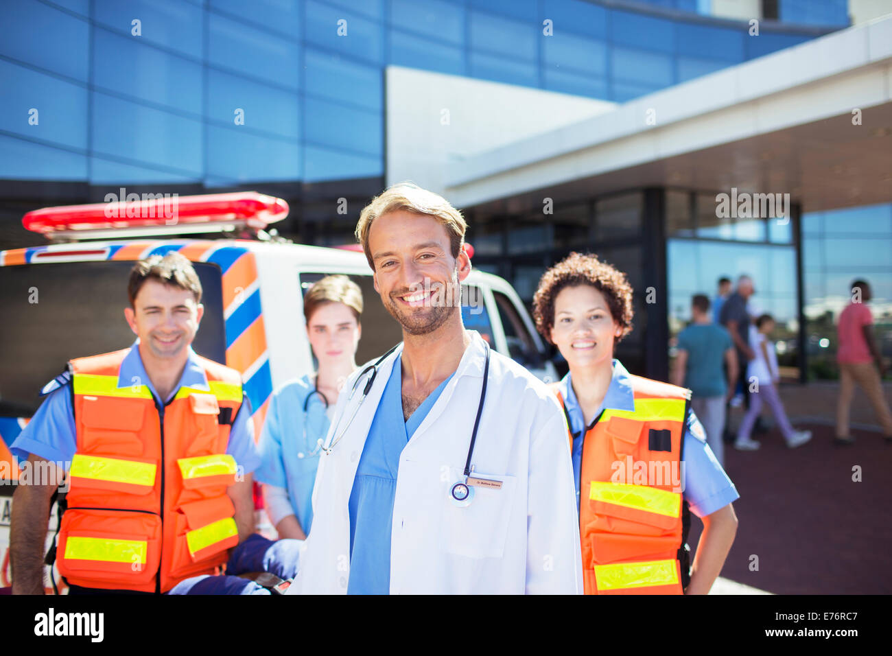 Arzt lächelnd mit Sanitätern in Krankenhaus-Parkplatz Stockfoto