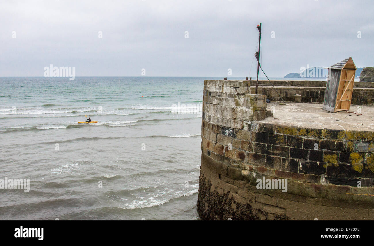 Ein Kanufahrer paddeln aus dem Hafen von Charlestown, ein Dorf und Hafen an der südlichen Küste von Cornwall, England UK Stockfoto