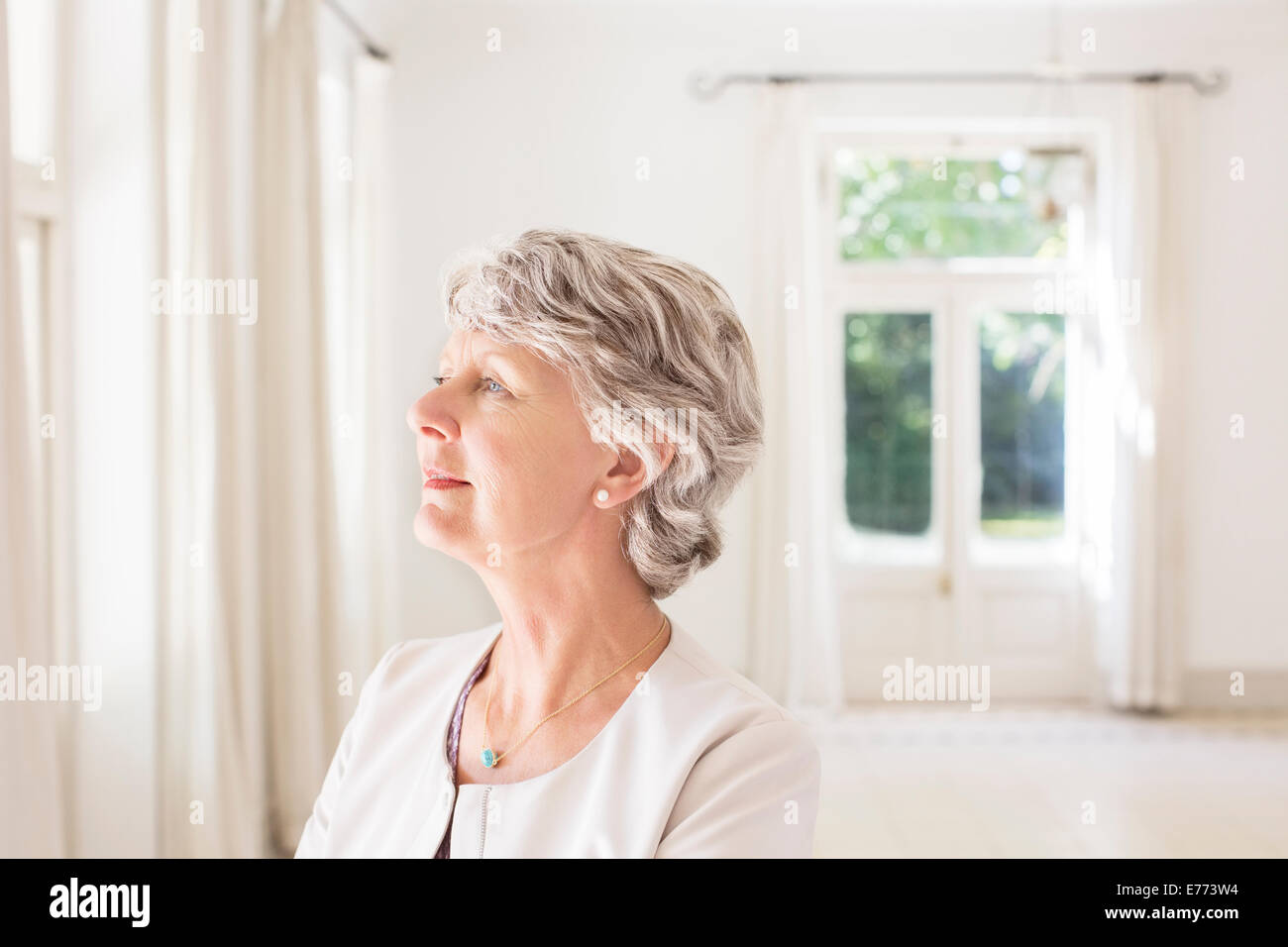 Ältere Frau mit Blick auf Wohnraum Stockfoto