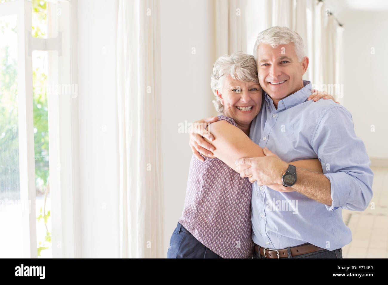 Älteres Ehepaar umarmt im Wohnraum Stockfoto