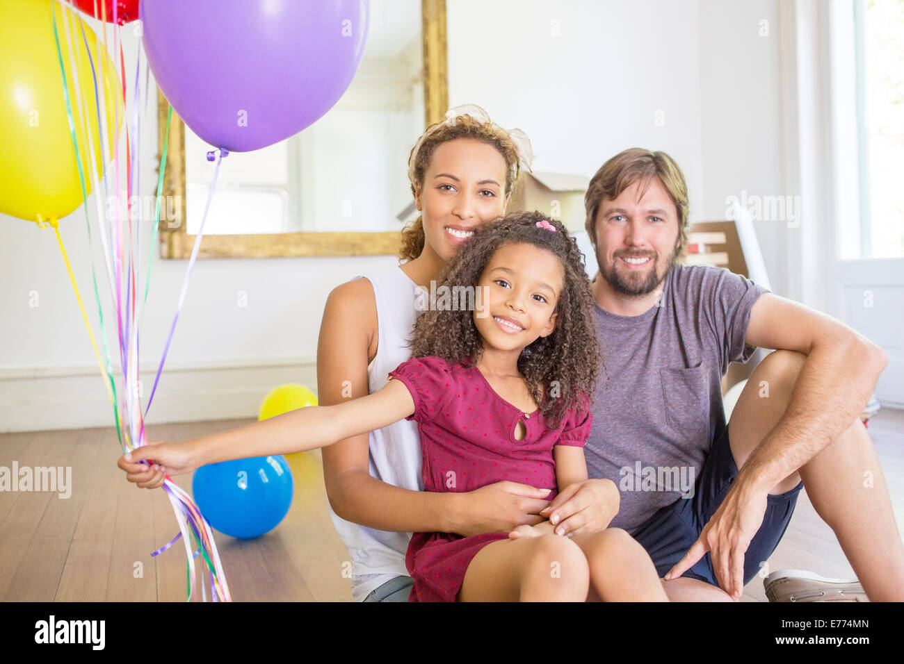 Familie sitzt im Wohnraum mit Luftballons Stockfoto