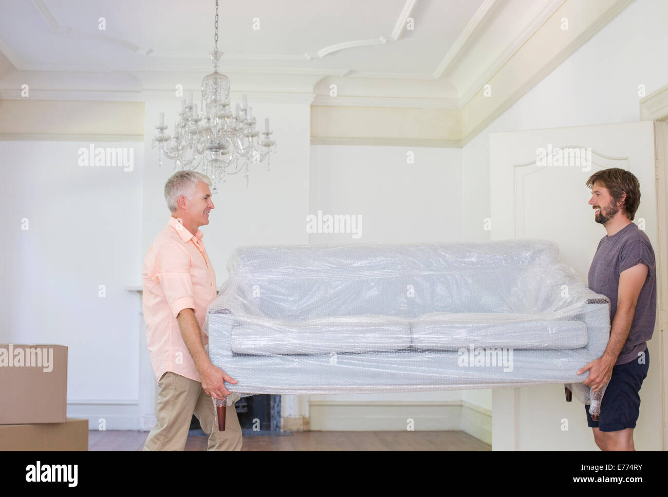 Vater und Sohn tragen couch in Wohnraum Stockfoto