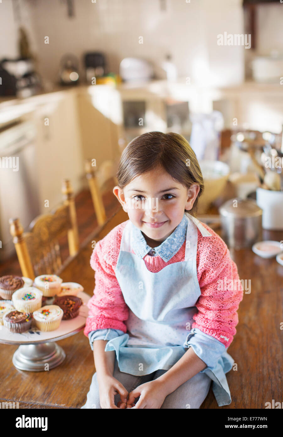 Junges Mädchen sitzen am Küchentisch in der Nähe von cupcakes Stockfoto