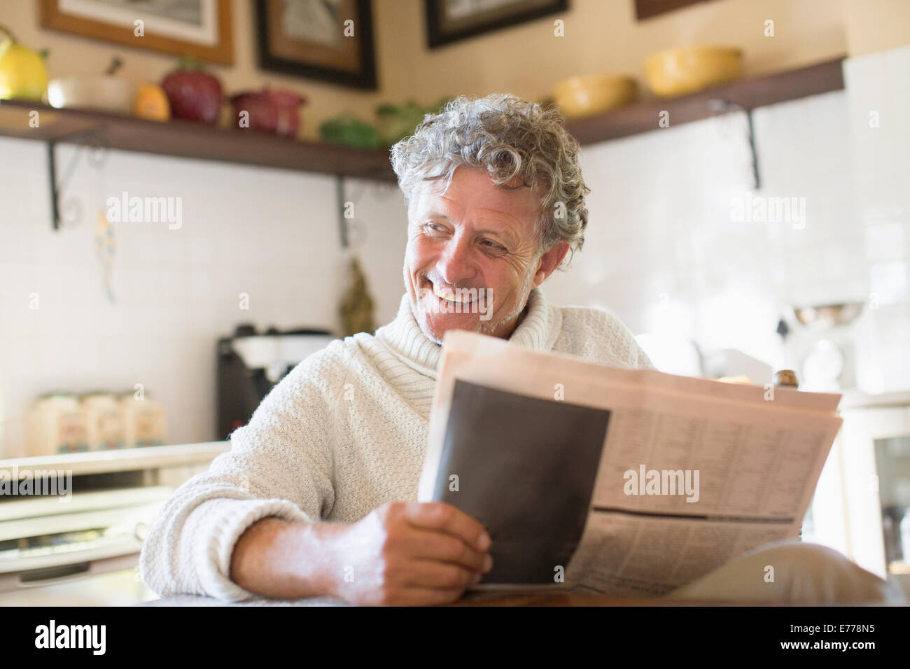 Ältere Mann liest Zeitung in Küche Stockfoto