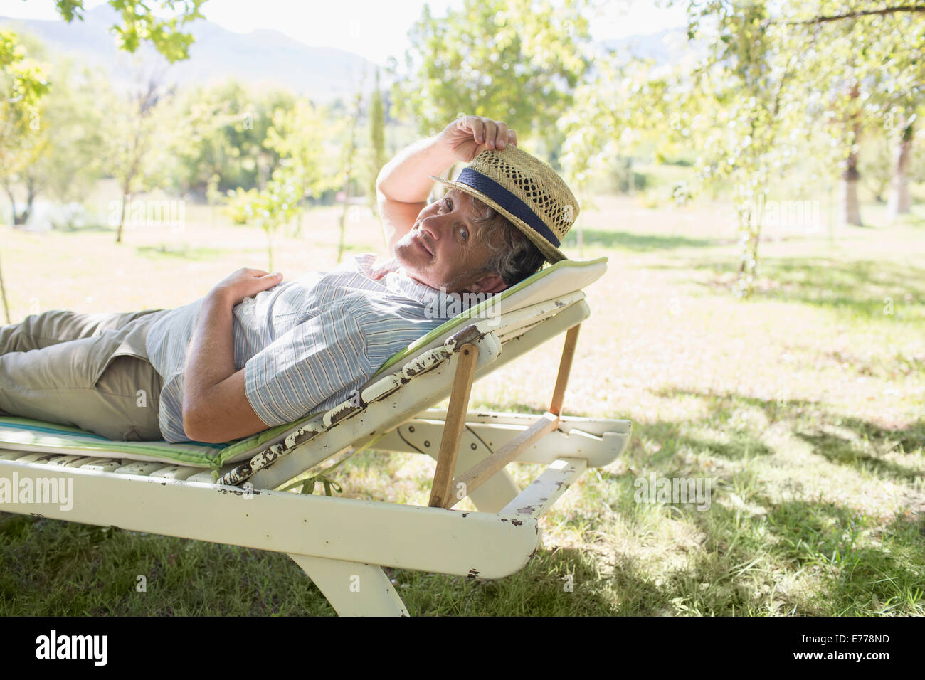 Älterer Mann entspannend auf Rasen Stuhl im freien Stockfoto