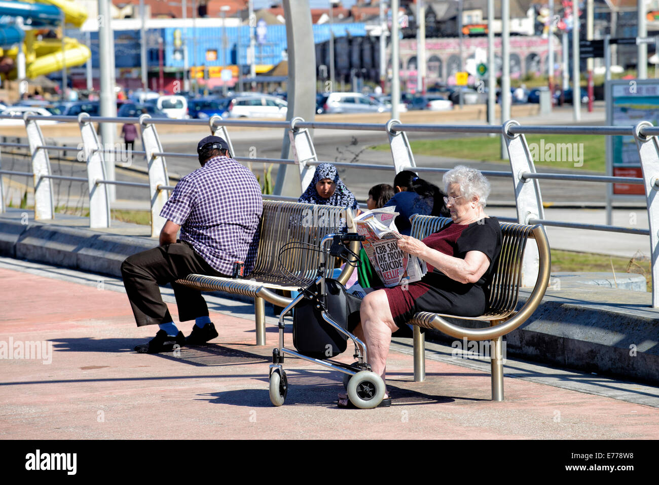 Ältere Dame Lesen Boulevardzeitung auf der Promenade in Blackpool Stockfoto