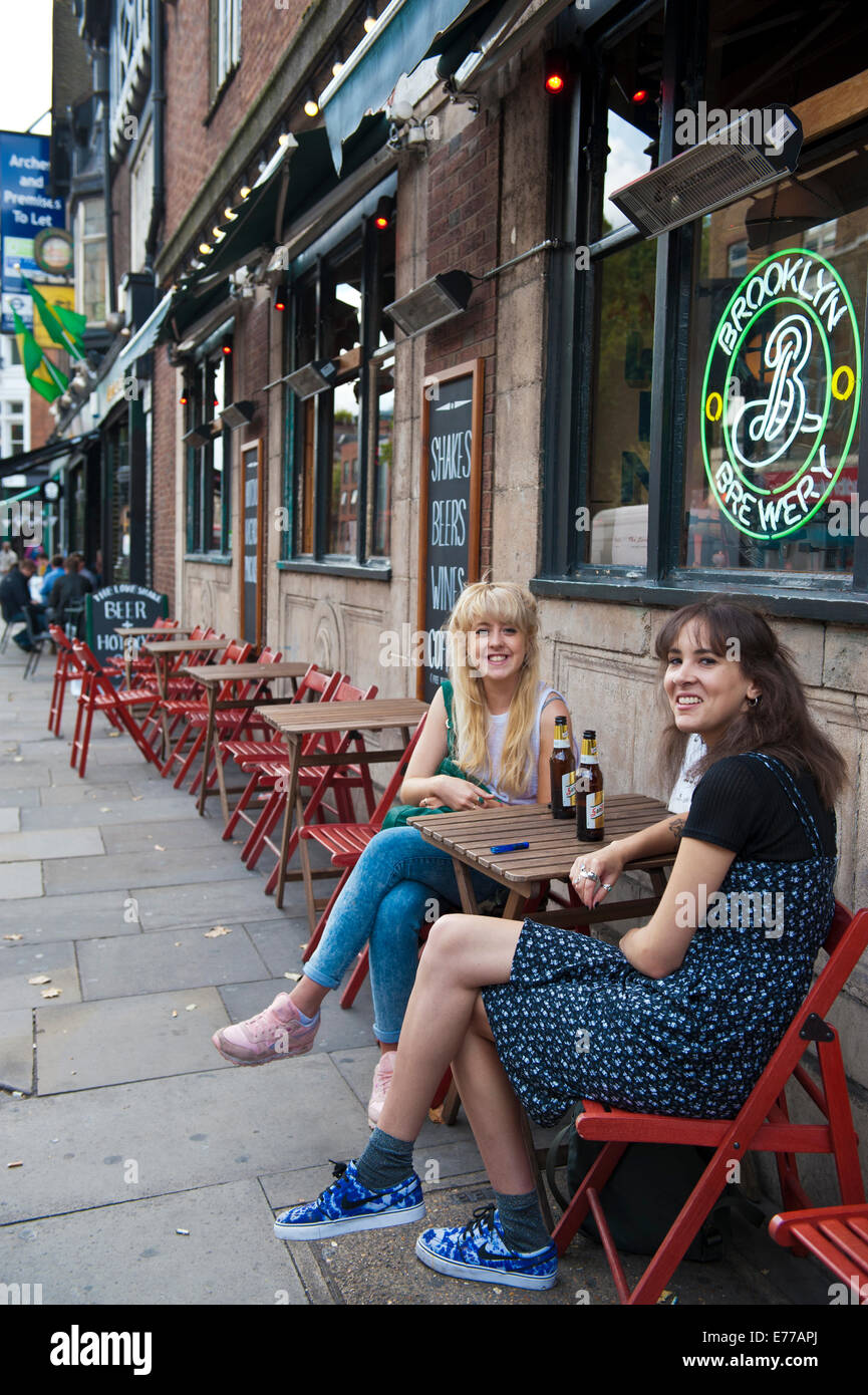 Zwei Mädchen teilen ein Bier in Kingsland Road in Shoreditch Stockfoto