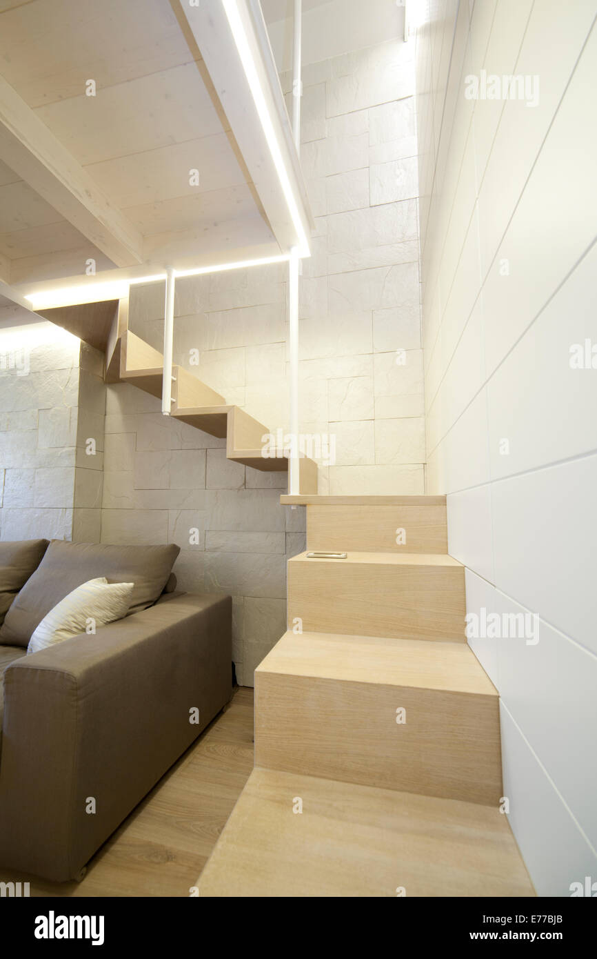 Modernes Wohnzimmer mit Treppe zu einem versteckten Raum im Obergeschoss. Detail der speziell angefertigten Treppen Stockfoto