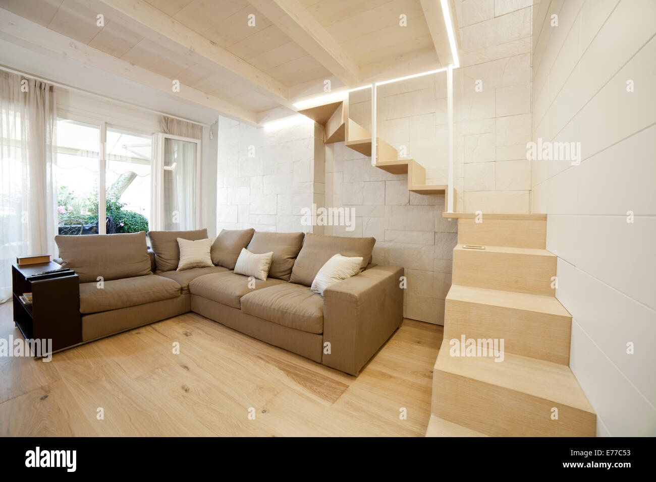 Modernes Wohnzimmer mit Treppe zu einem versteckten Raum im Obergeschoss Stockfoto