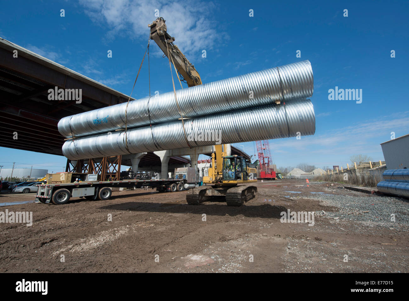Baggerlader verschiebt riesige Metall Leerrohre für New Haven Hafen Crossing Projekt. Stockfoto
