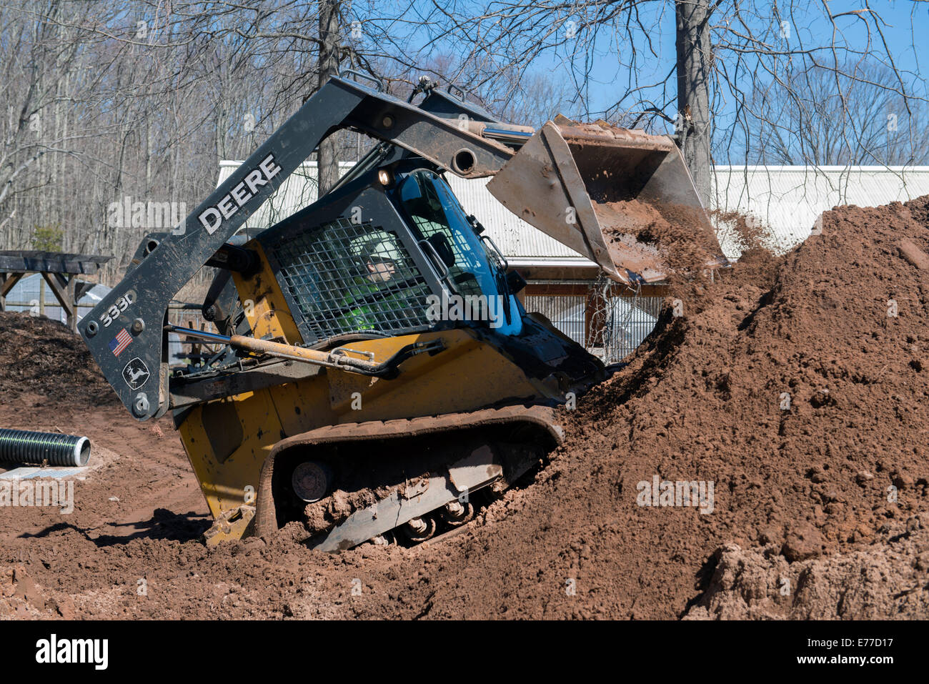 Deere Steer Kompaktlader zieht Schmutz. Stockfoto