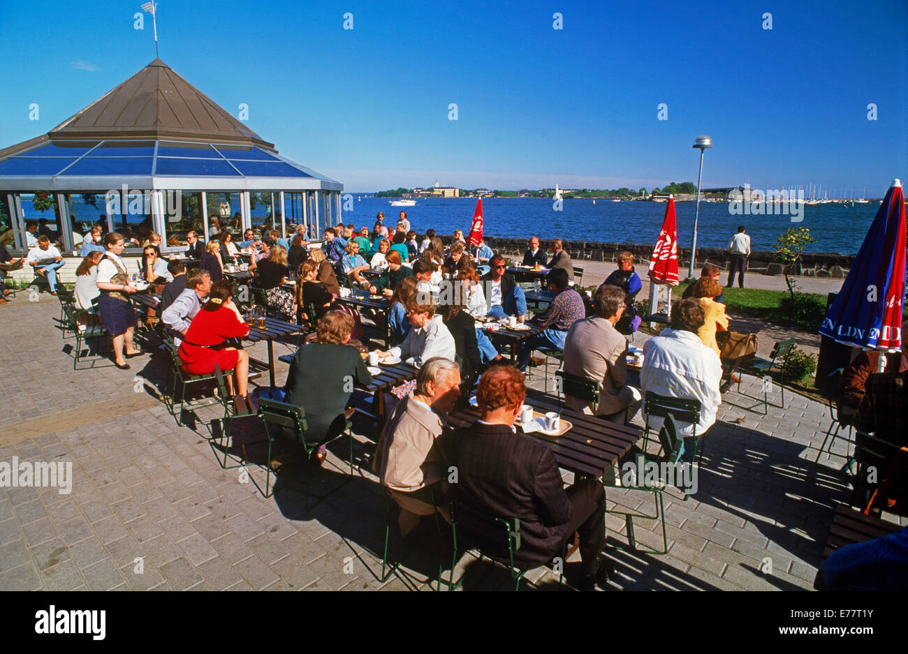 Touristen im Sommer und Finnen im Outdoor-Restaurant namens Ursula nahe Hafen an der Ostsee in Helsinki, Finnland Stockfoto