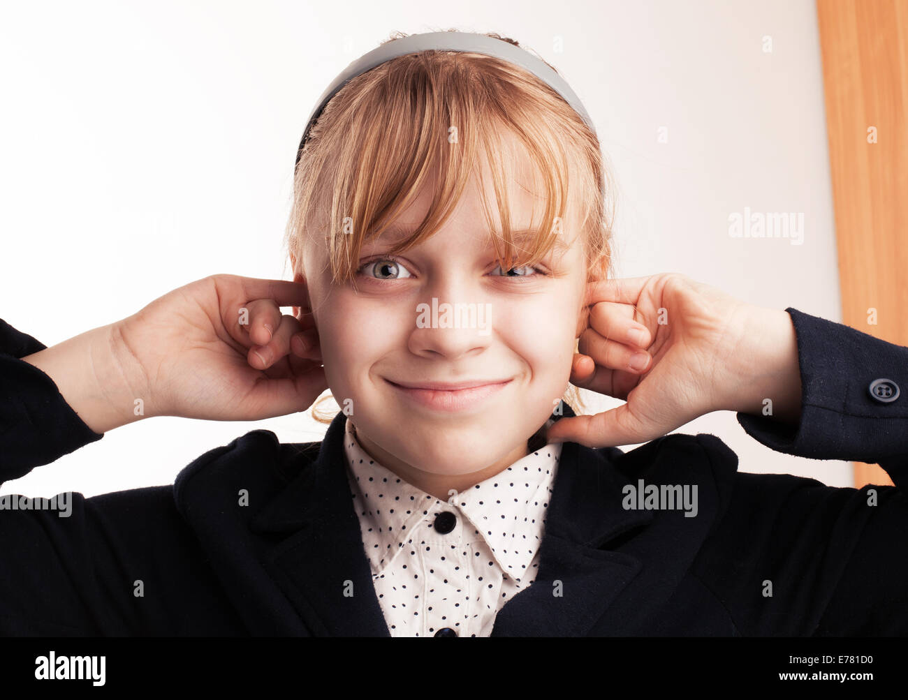Blonde Schülerin lächelnd Stecker Fingern in den Ohren Stockfoto