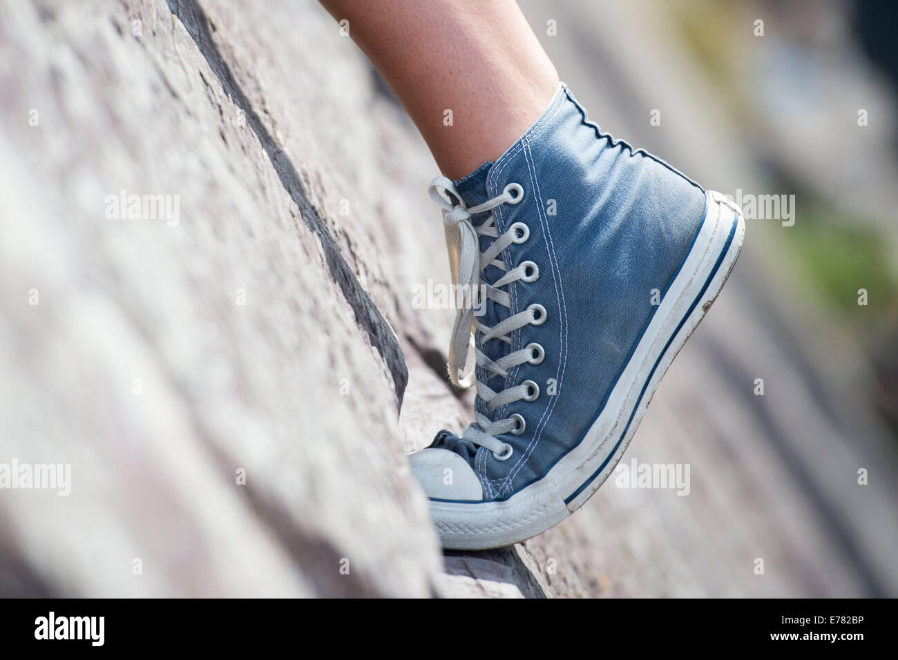 Ein Mädchen Fuß gesehen tragen Converse Dehnung beim Klettern. Stockfoto